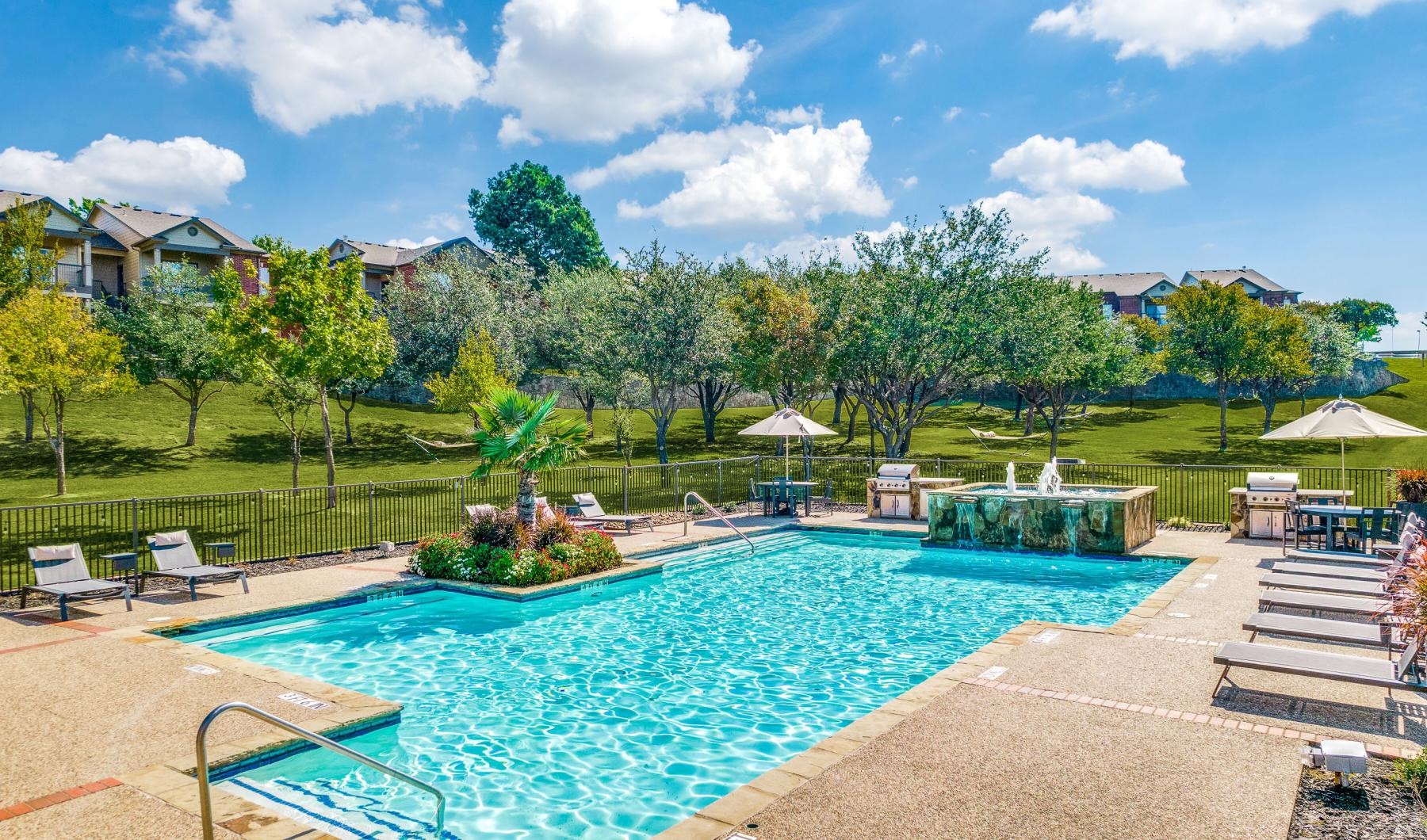 a swimming pool with a fence around it and trees in the back